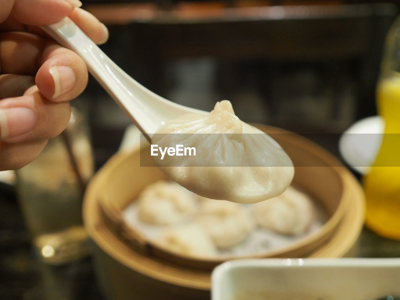 Close-up of cropped hand holding chinese dumpling on spoon