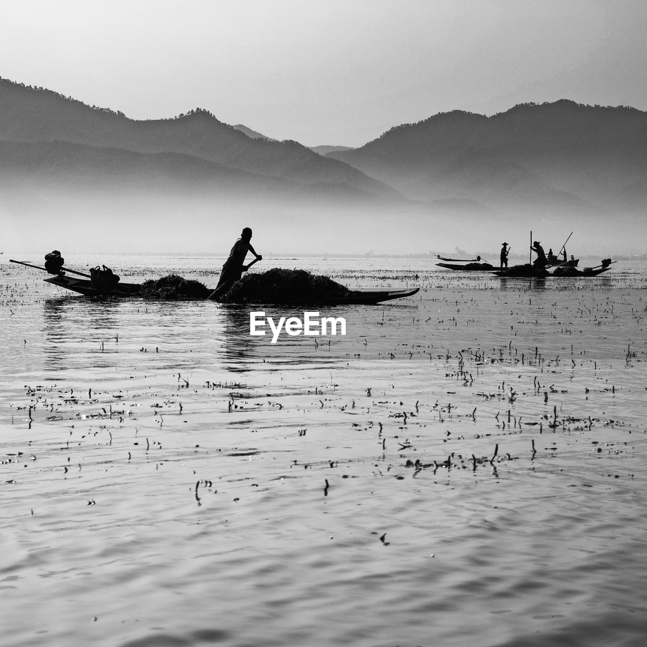 People fishing on shore by sea against sky