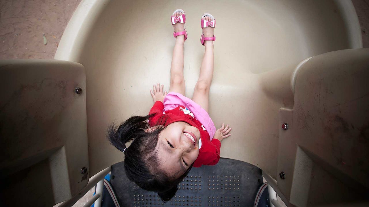 High angle portrait of girl sitting on slide at playground