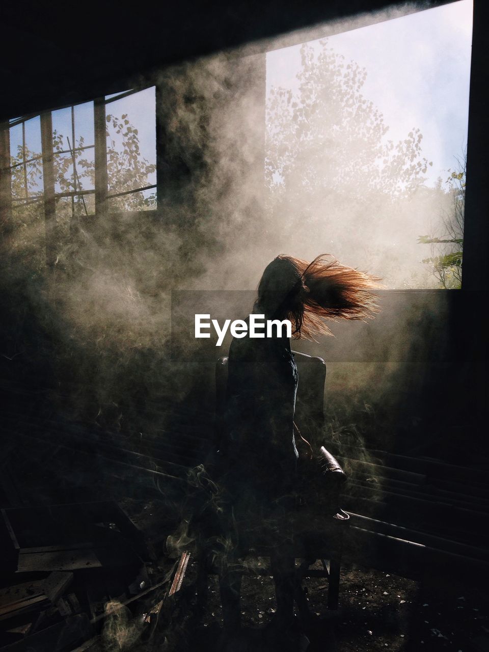 Sunlight falling on woman with tousled hair at abandoned building