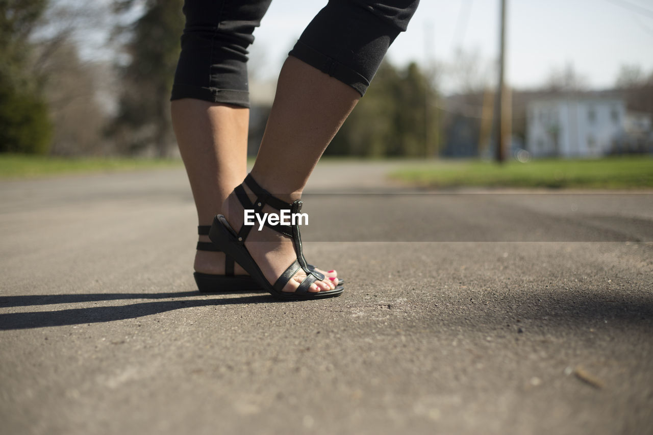 Low section of woman standing on road