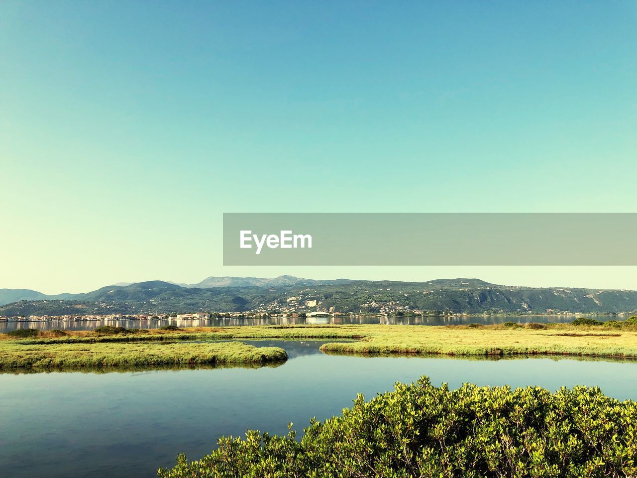 Scenic view of lake against clear blue sky