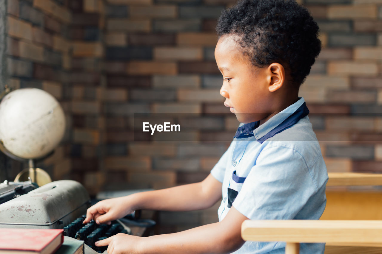 Side view of boy using typewriter