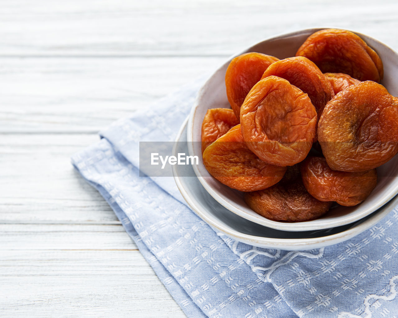 Dried apricots on white rustic wooden background