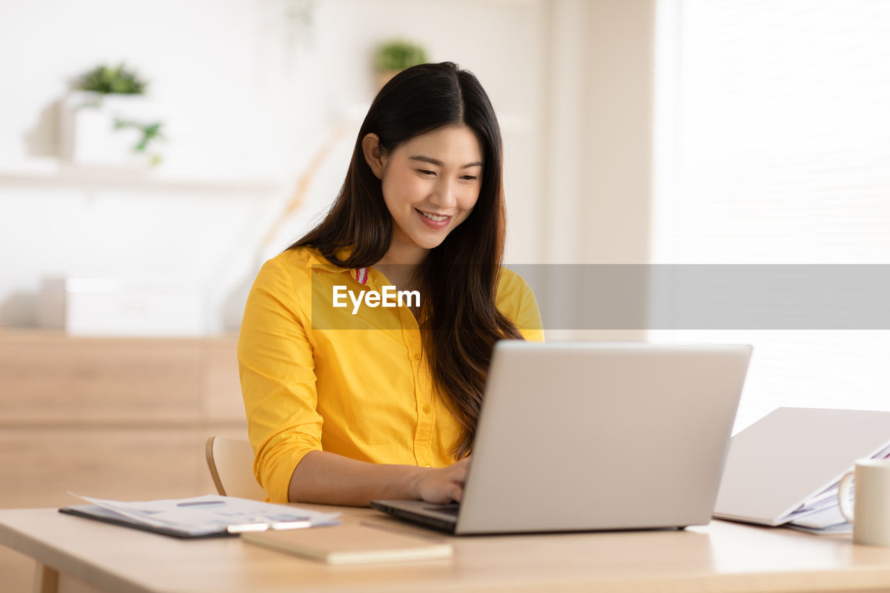 Young woman using phone while sitting on table