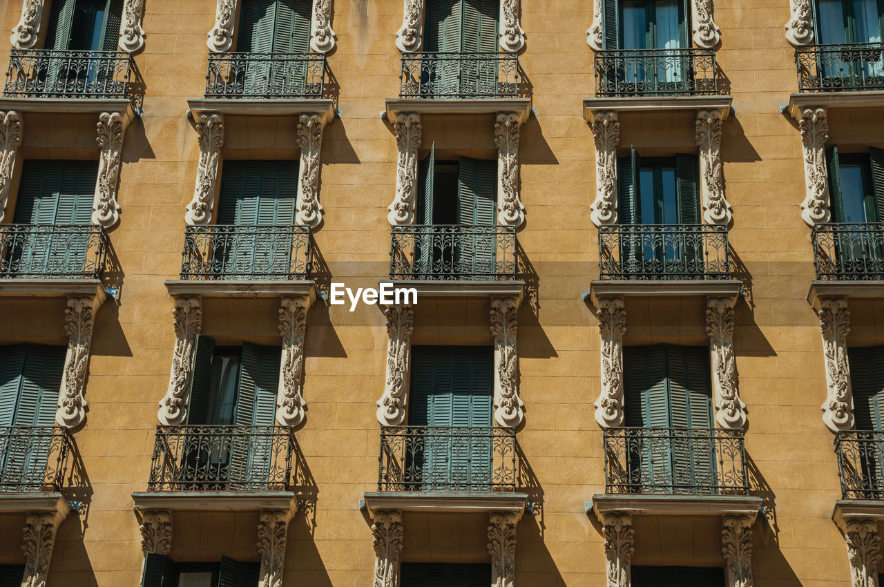 Old building with colorful facade and closed windows with iron balustrade in madrid, spain.