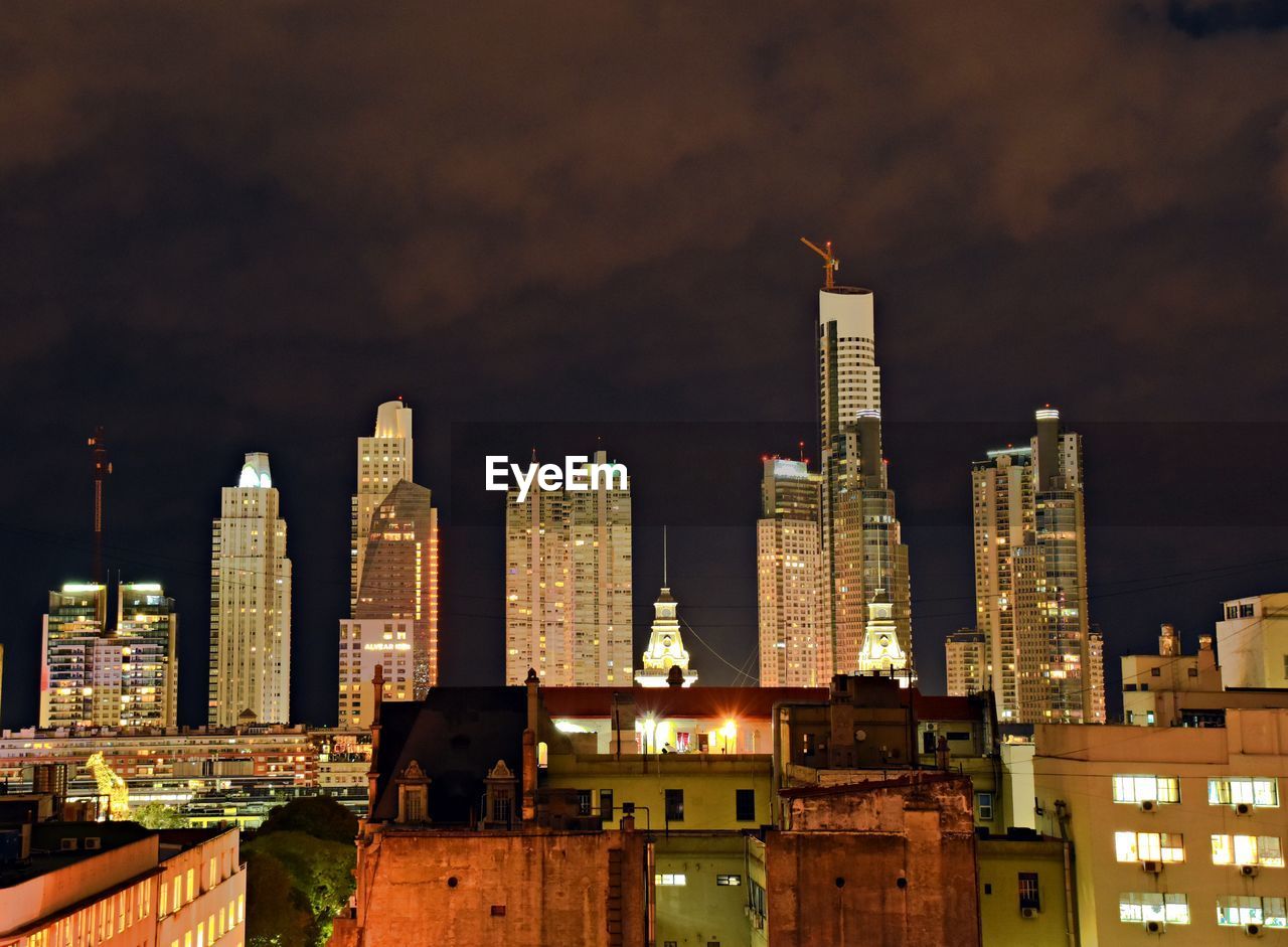 Modern buildings in city against sky at night