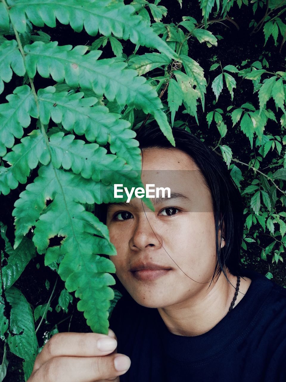 CLOSE-UP PORTRAIT OF YOUNG WOMAN WITH LEAVES