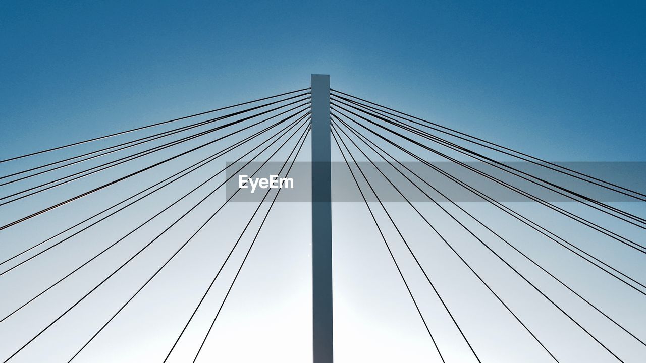 Low angle view of suspension bridge against clear blue sky