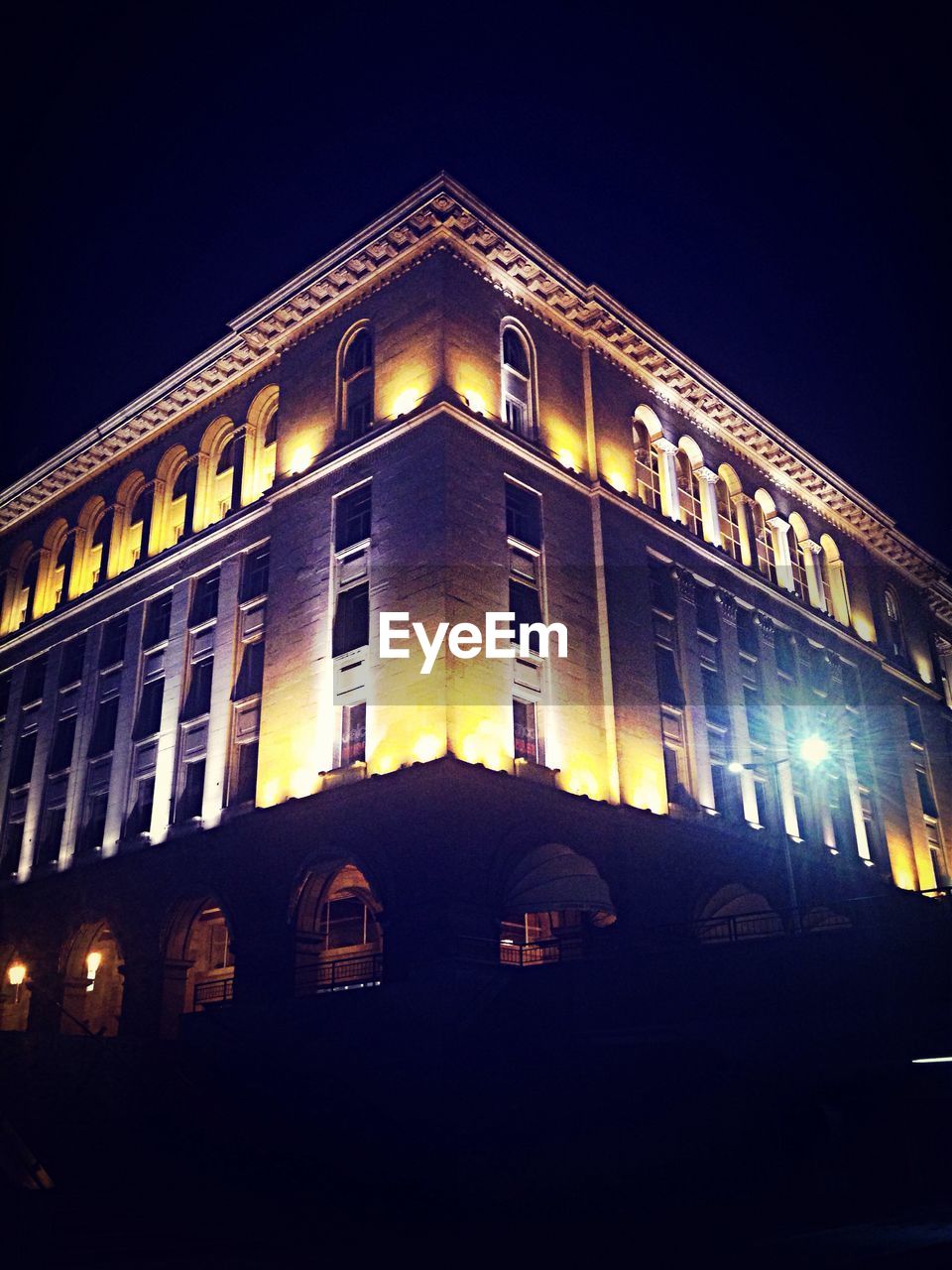 LOW ANGLE VIEW OF ILLUMINATED BUILDINGS AT NIGHT