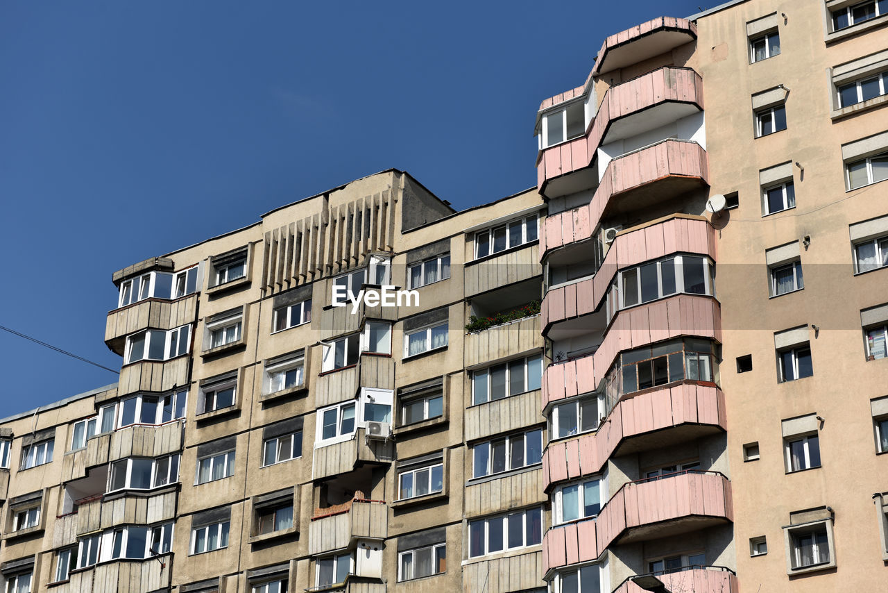 architecture, building exterior, built structure, building, tower block, window, city, residential district, apartment, neighbourhood, residential area, low angle view, urban area, sky, no people, house, condominium, facade, nature, downtown, clear sky, in a row, outdoors, balcony, repetition, home ownership, business finance and industry, day, community, sunlight, shield, sunny, shielding, construction industry