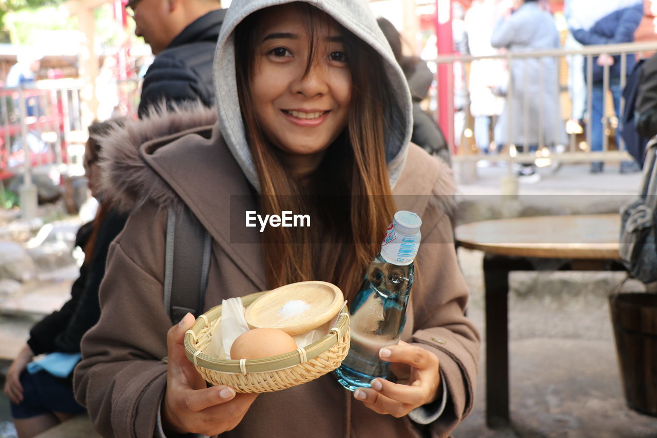 Portrait of woman holding food and drink