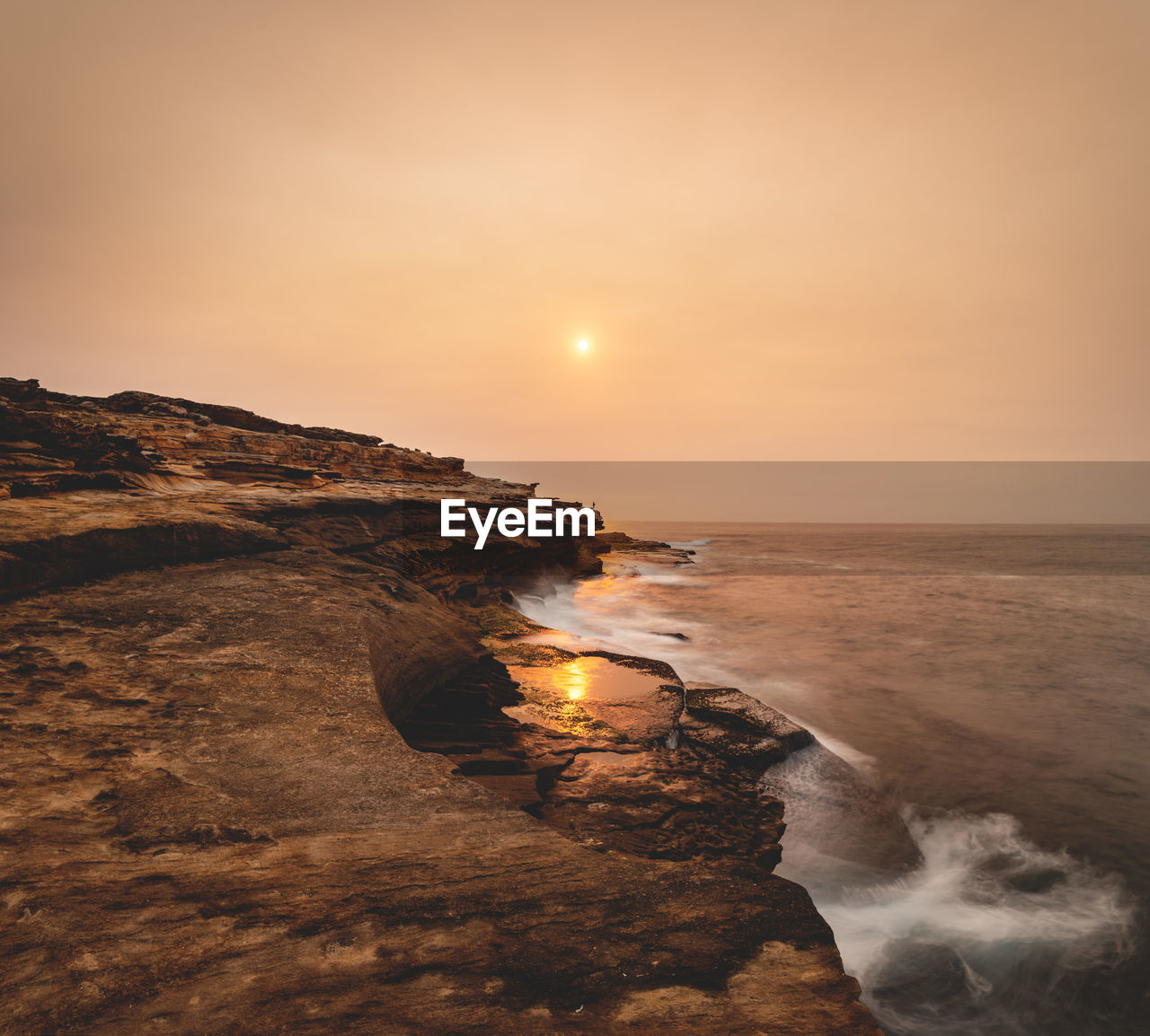 Scenic view of rock formation by sea against sky during sunset