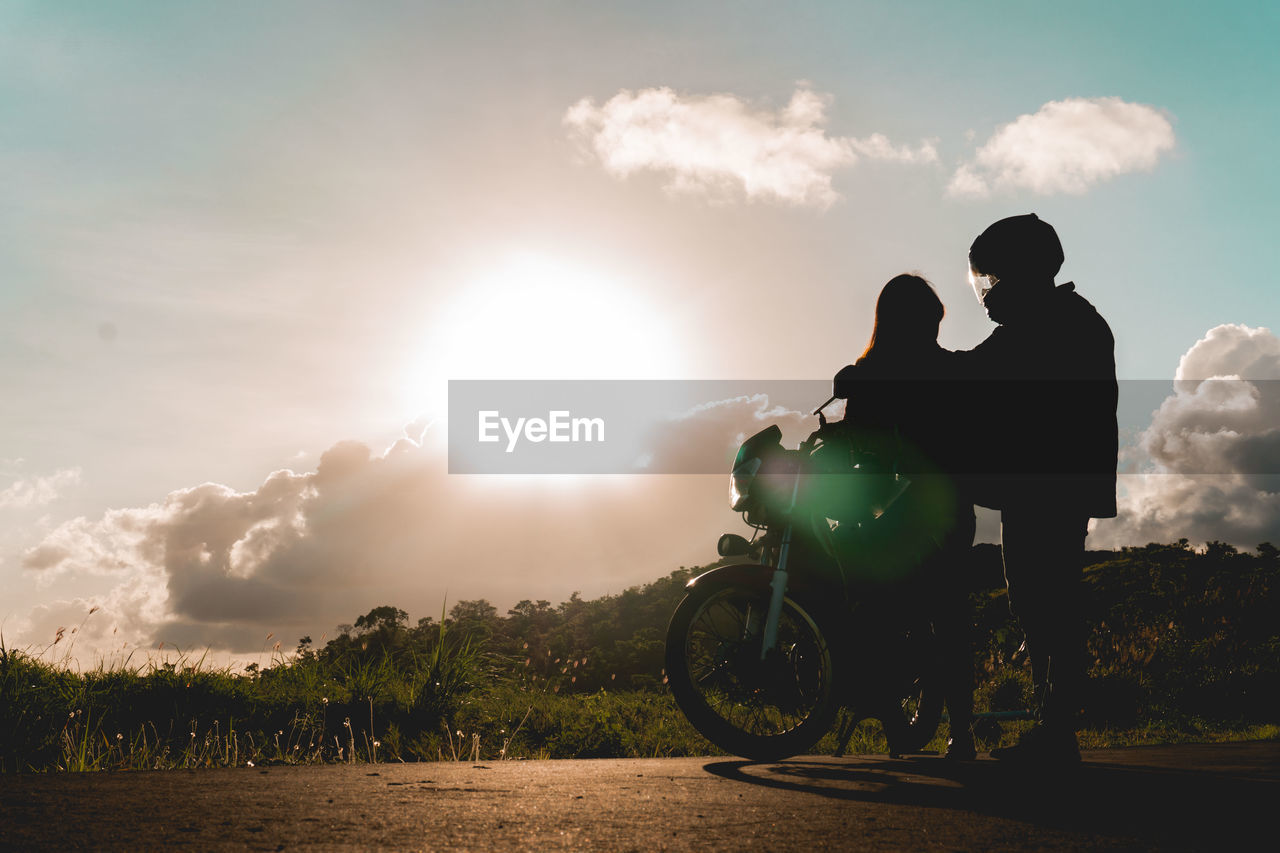 Low angle view of couple standing by motorcycle on land against sky