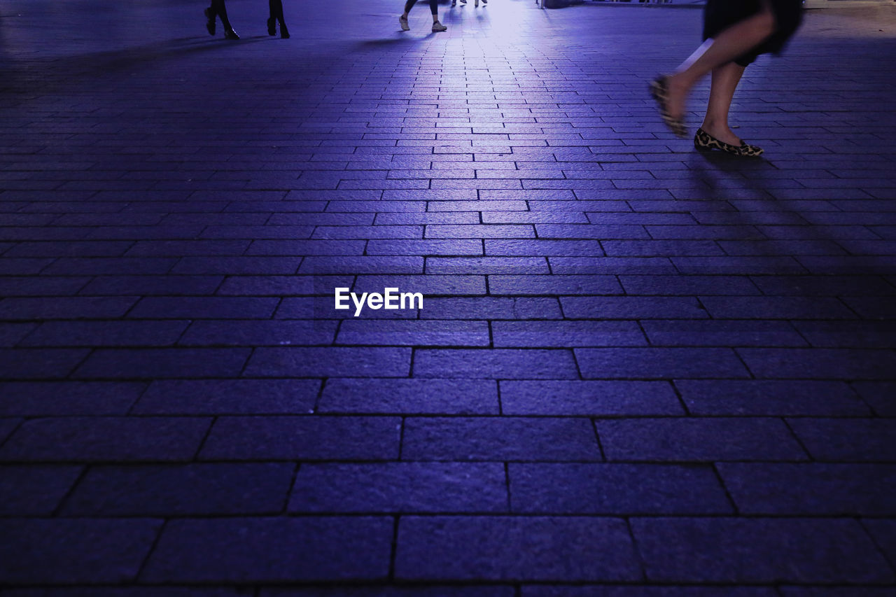 Low section of woman walking on street at night