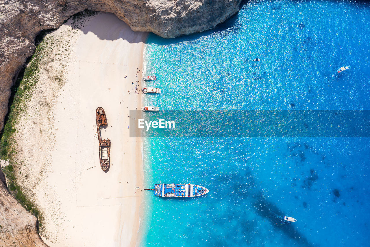 Aerial view of shipwreck at beach and boat in sea 