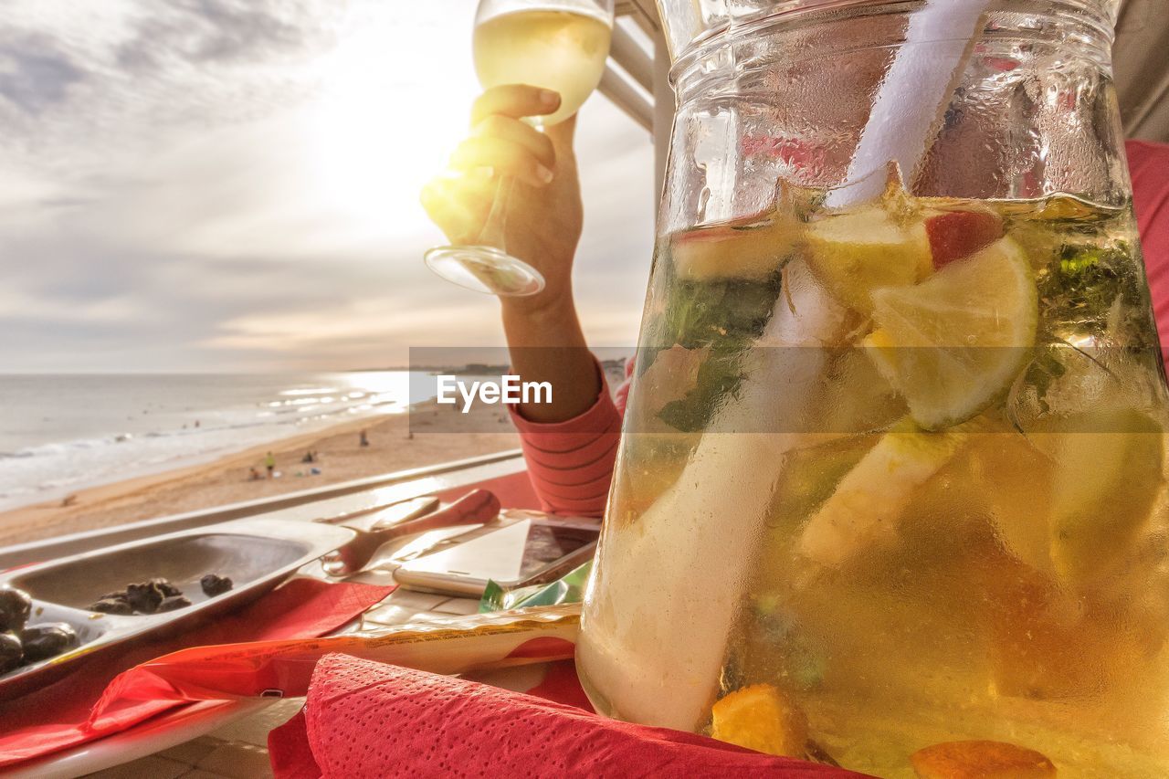 CLOSE-UP OF HAND HOLDING DRINK AT SEA