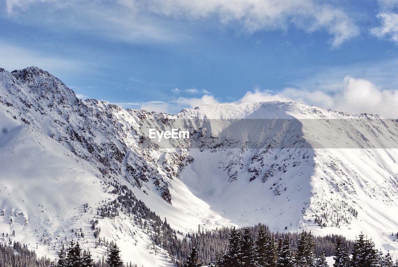 Low angle view of snowcapped mountains against cloudy sky