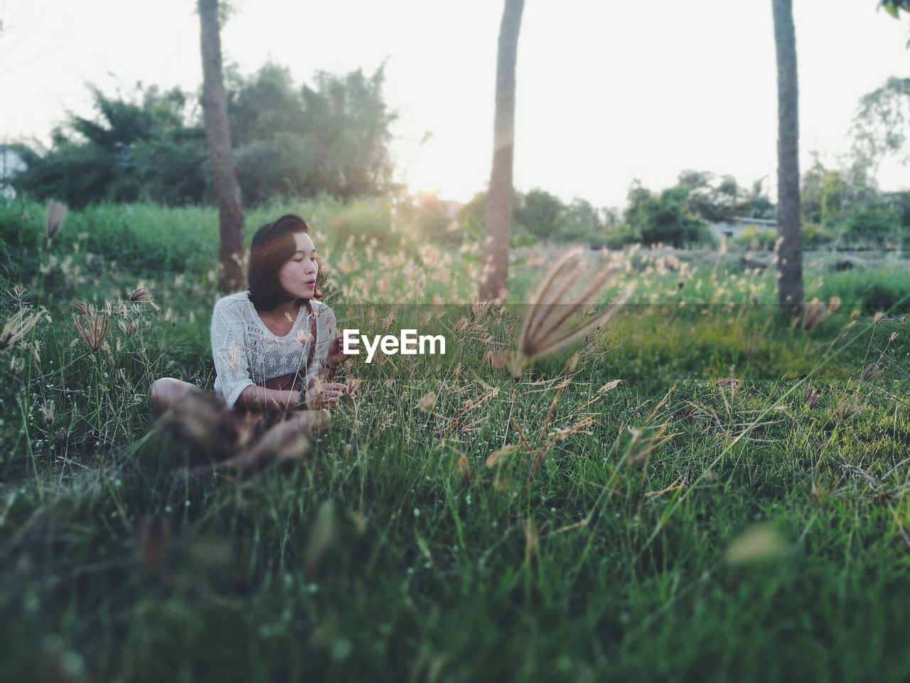 Mature woman sitting on grass during sunset