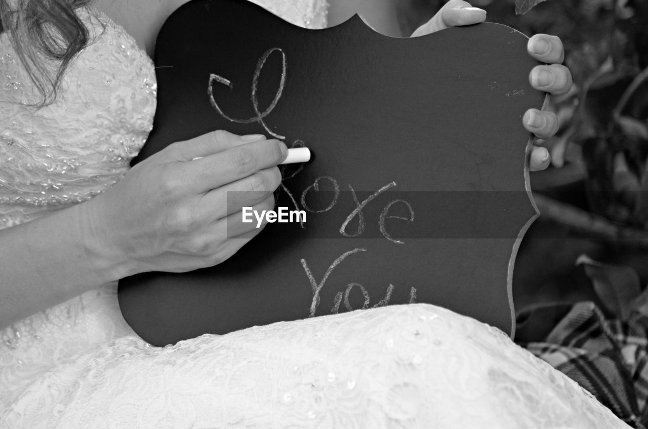 Midsection of bride writing in blackboard with chalk