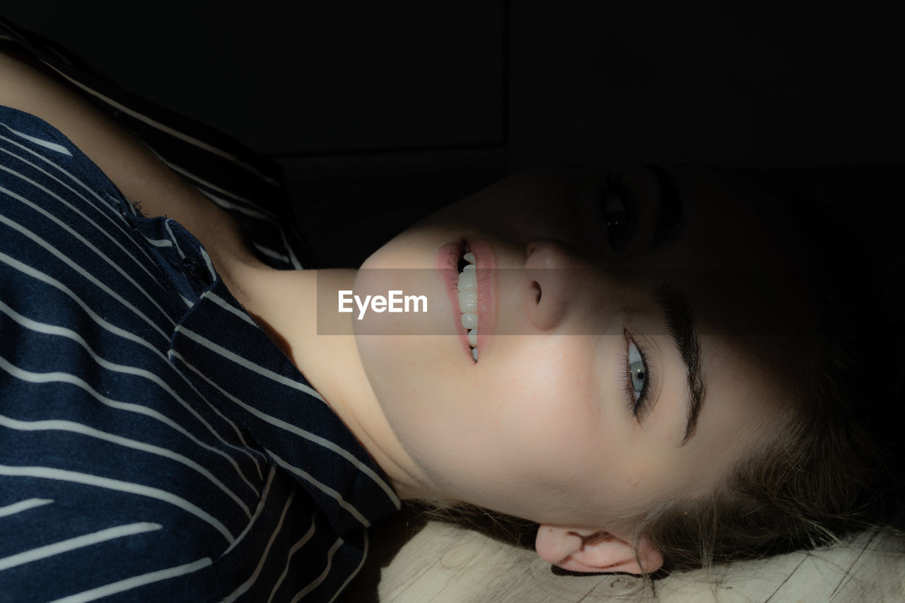 High angle portrait of young woman lying on floor in darkroom