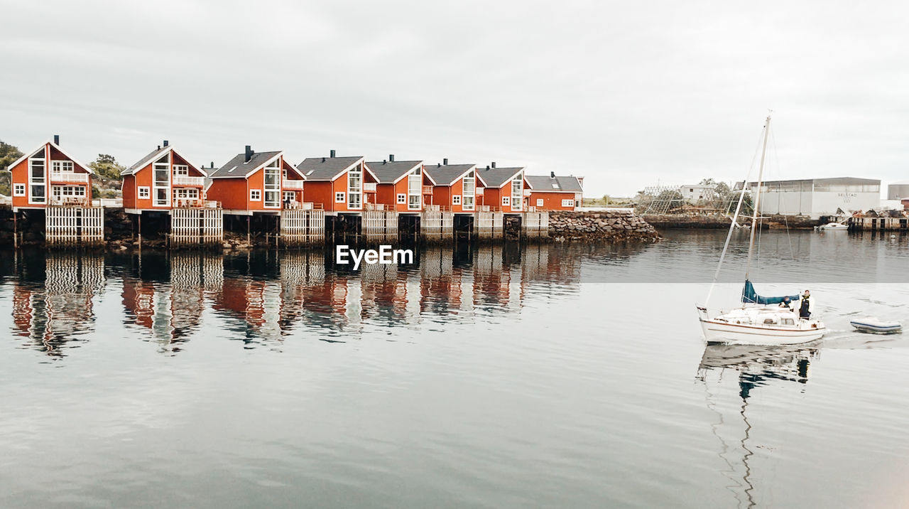 Boats moored in canal by buildings against sky