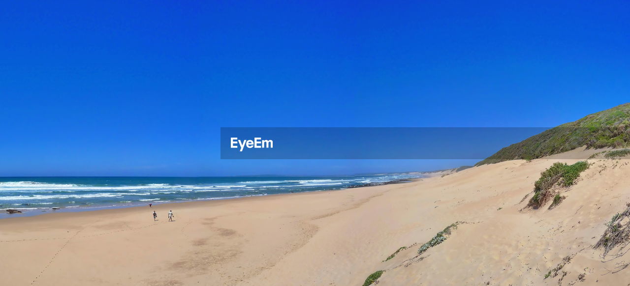 Scenic view of beach against clear blue sky