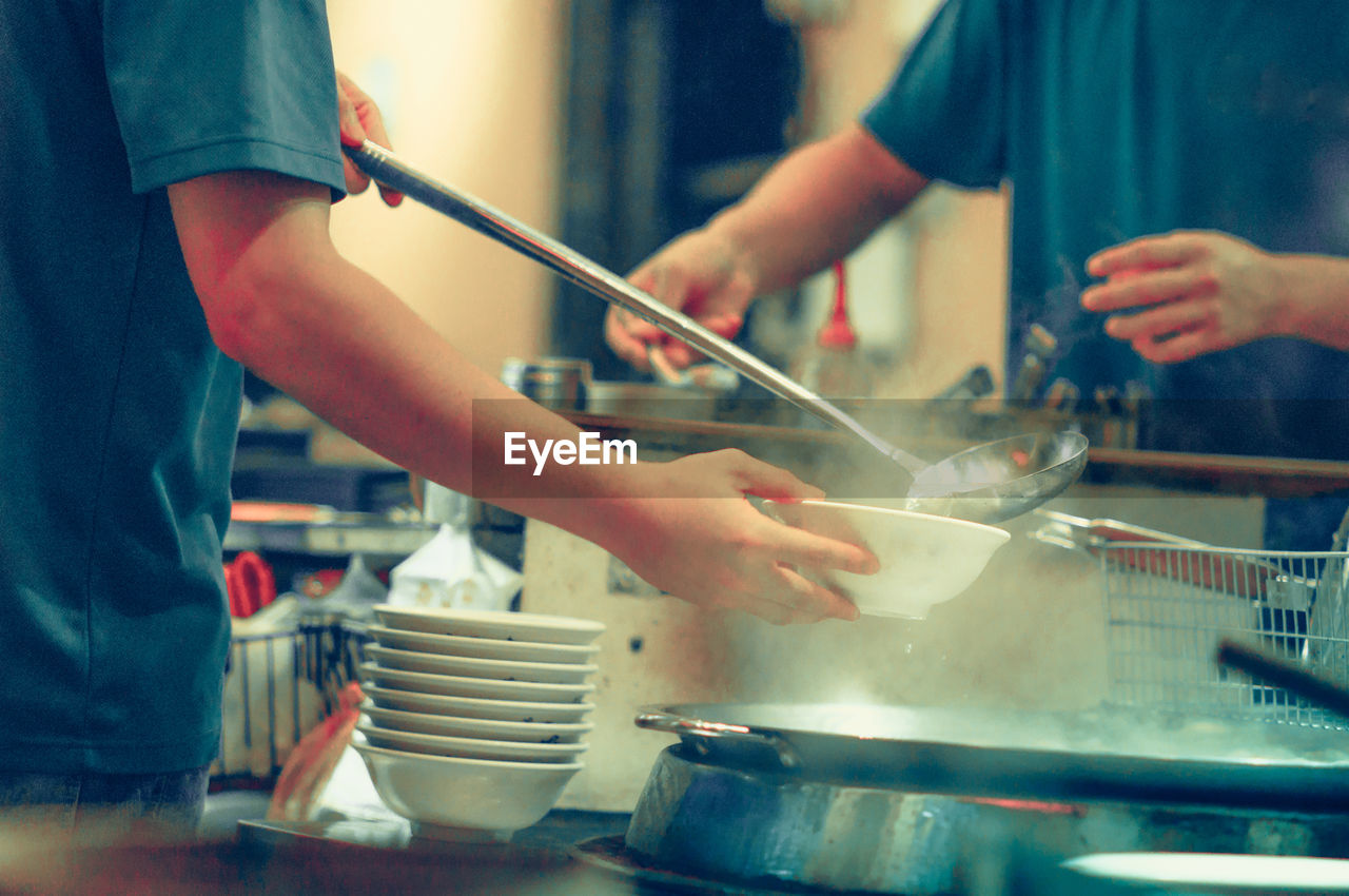 Midsection of men preparing food in restaurant kitchen