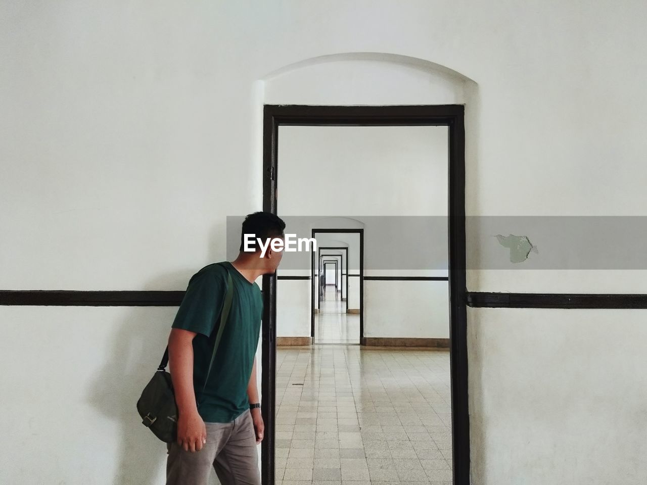 Young man looking at corridor through door