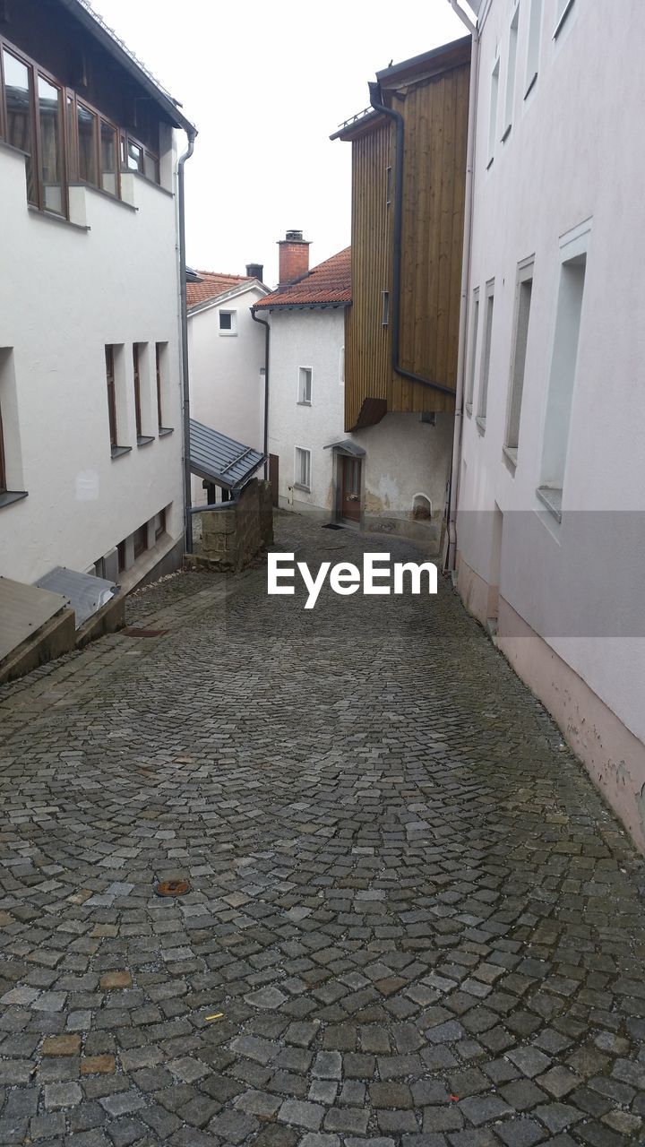 Cobblestone street amidst buildings against sky