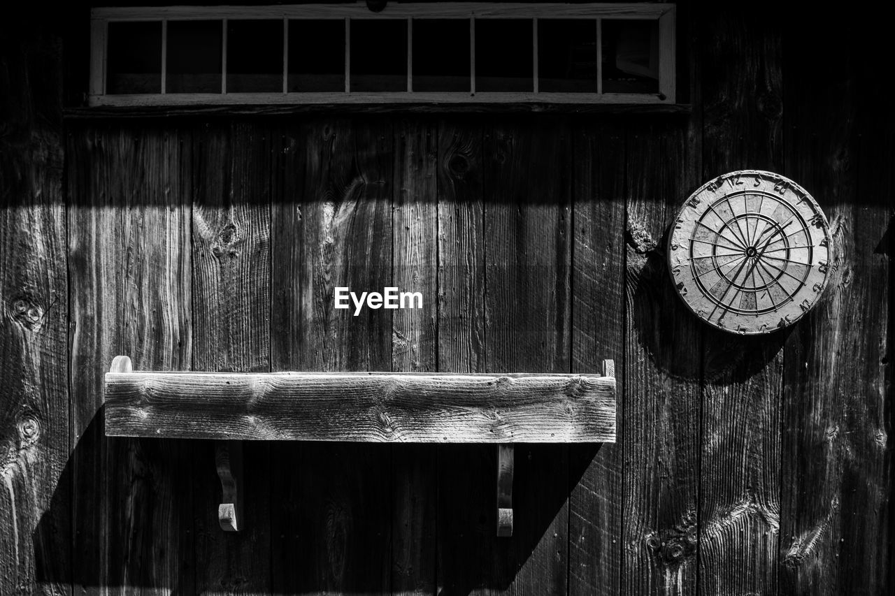 Close-up of wooden clock hanging on old door