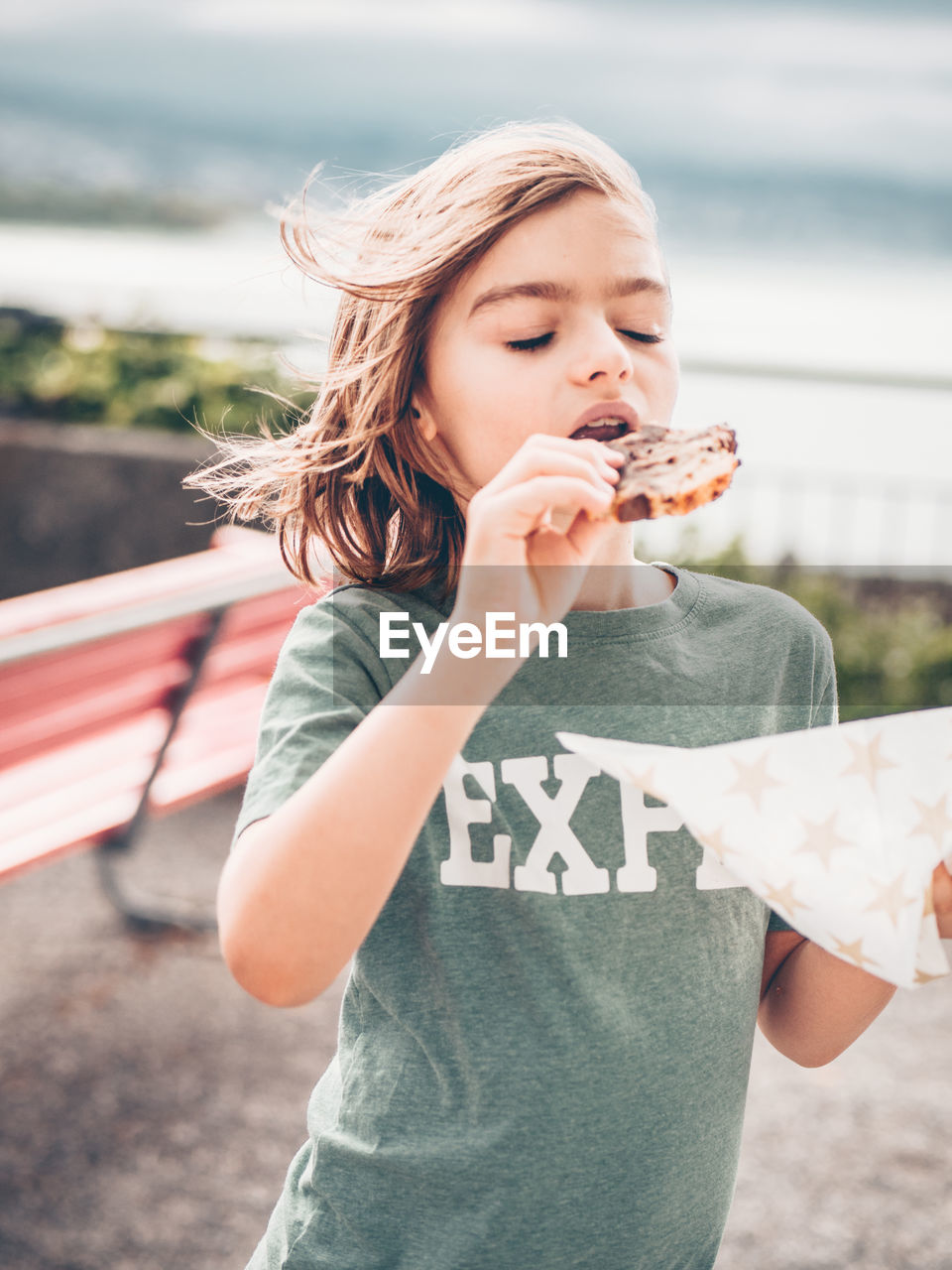 Close-up of cute boy with eyes closed eating food while standing outdoors