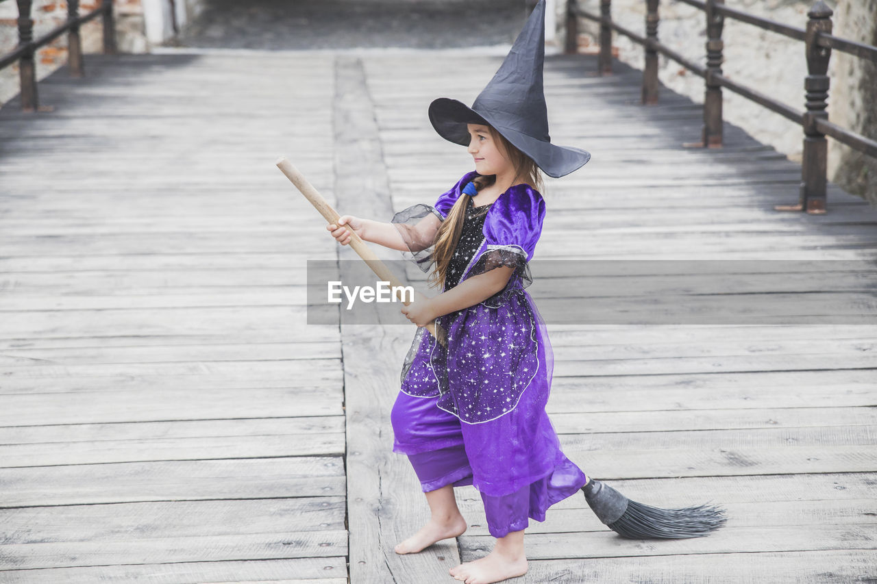 side view of girl standing on wooden wall