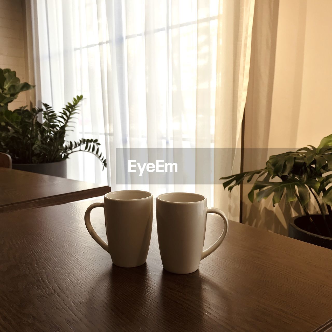 COFFEE CUP ON TABLE AGAINST WINDOW