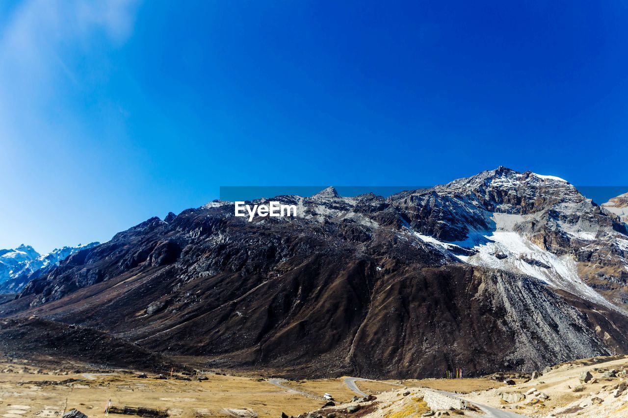 Scenic view of snowcapped mountains against clear blue sky