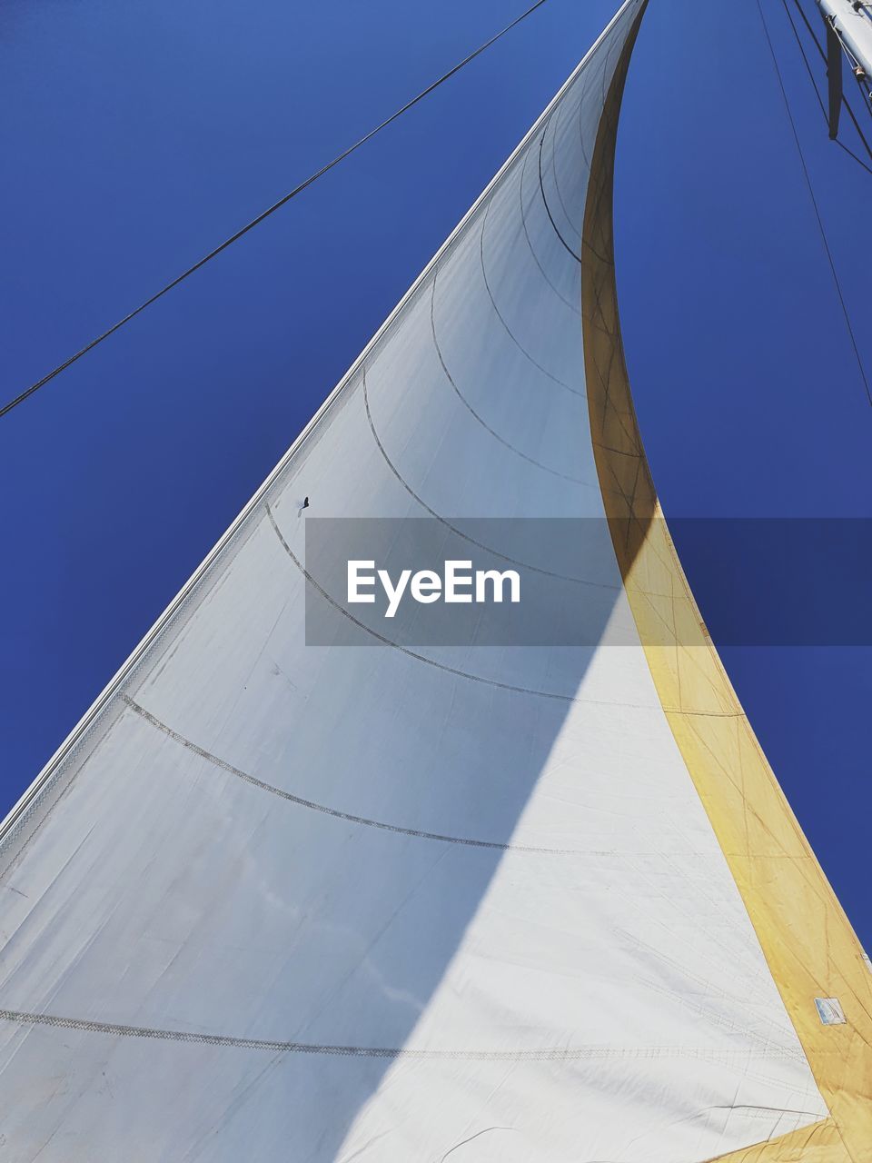 Low angle view of sailboat against clear blue sky