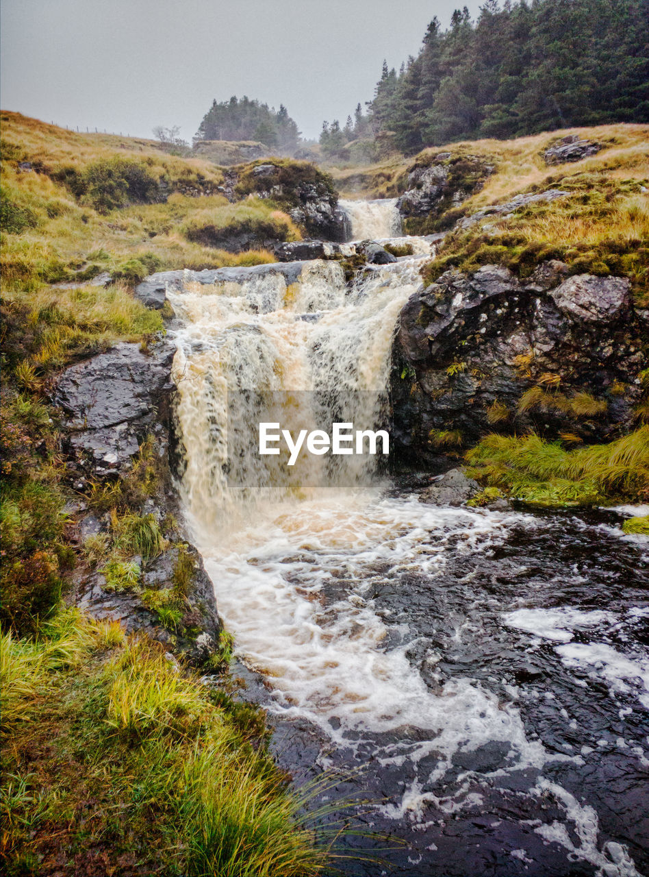 Waterfall in forest against sky