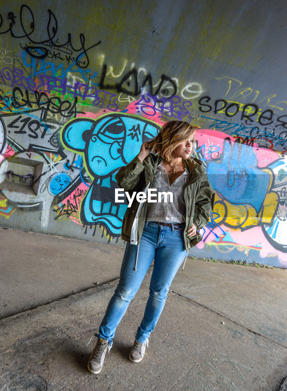 FULL LENGTH OF WOMAN ON GRAFFITI WALL