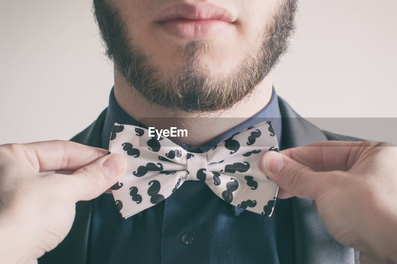 Close-up of young man tying bow tie