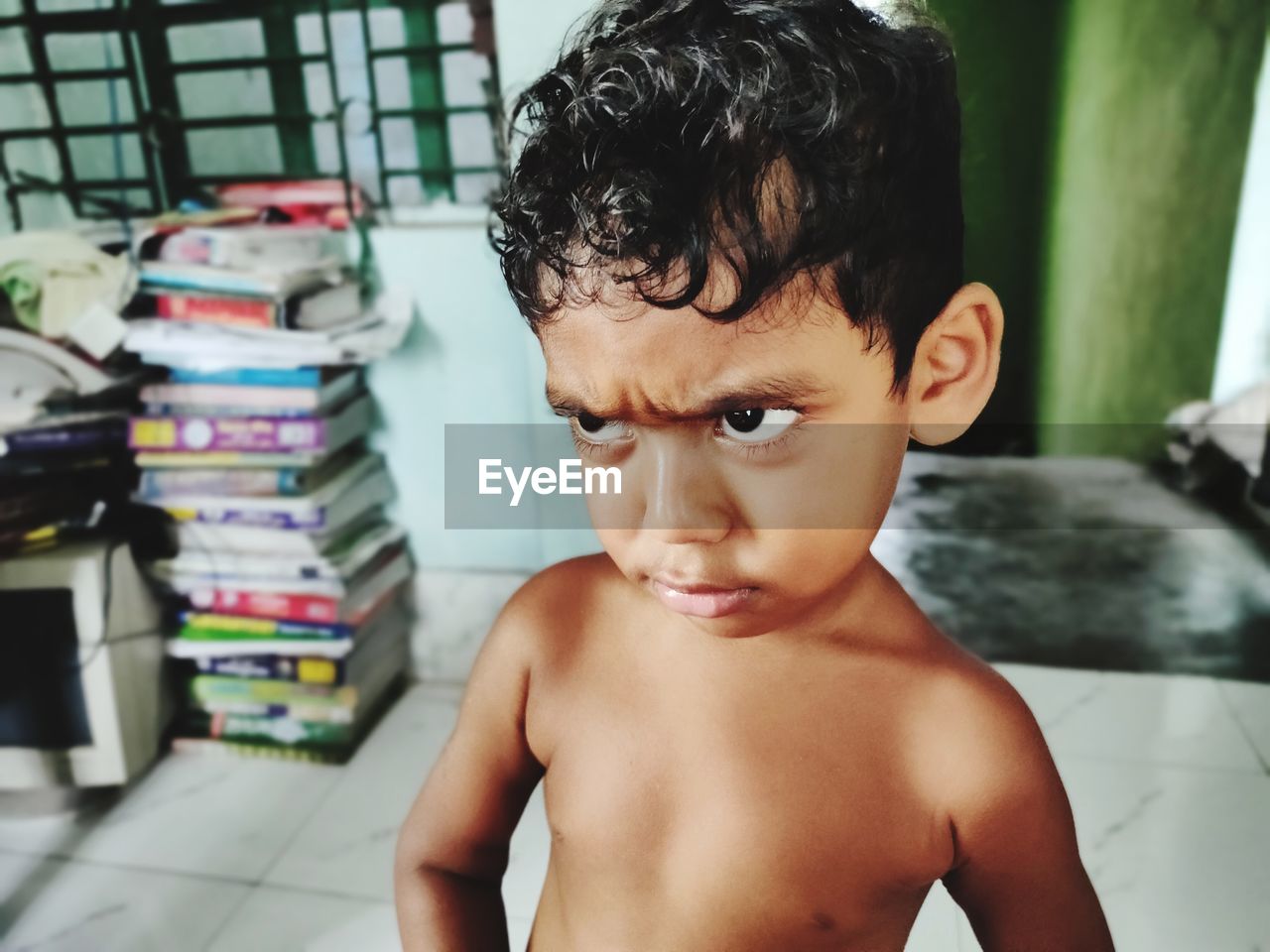 Close-up of shirtless boy looking away standing at home