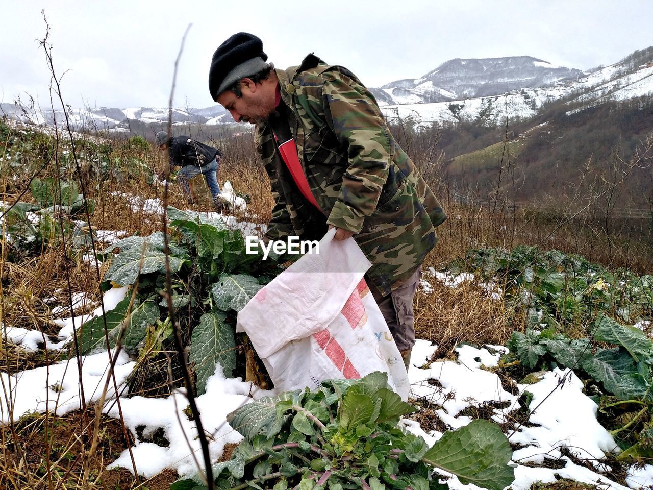 YOUNG MAN STANDING ON SNOW COVERED FIELD