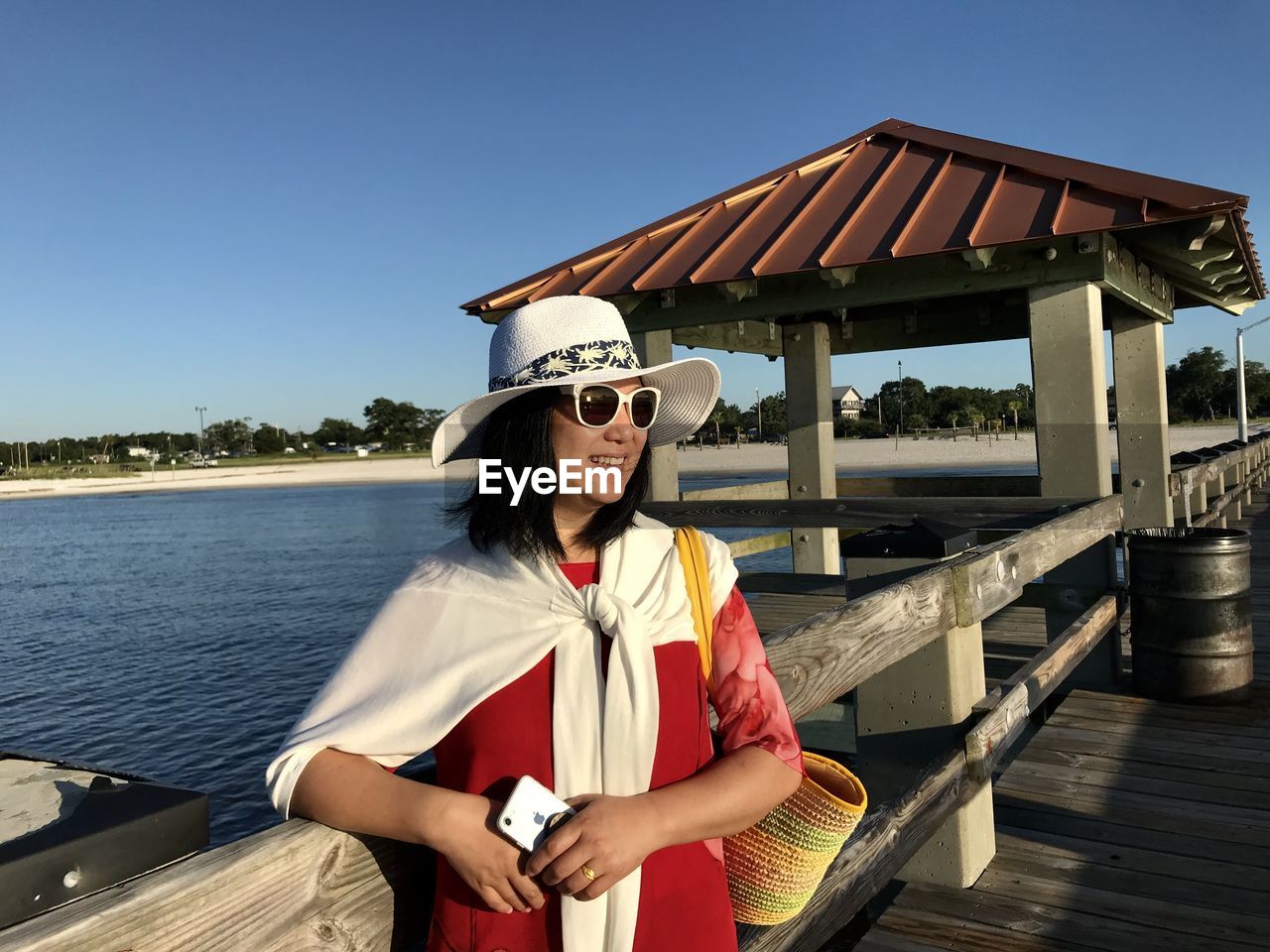 YOUNG WOMAN WEARING SUNGLASSES STANDING AGAINST BUILDING