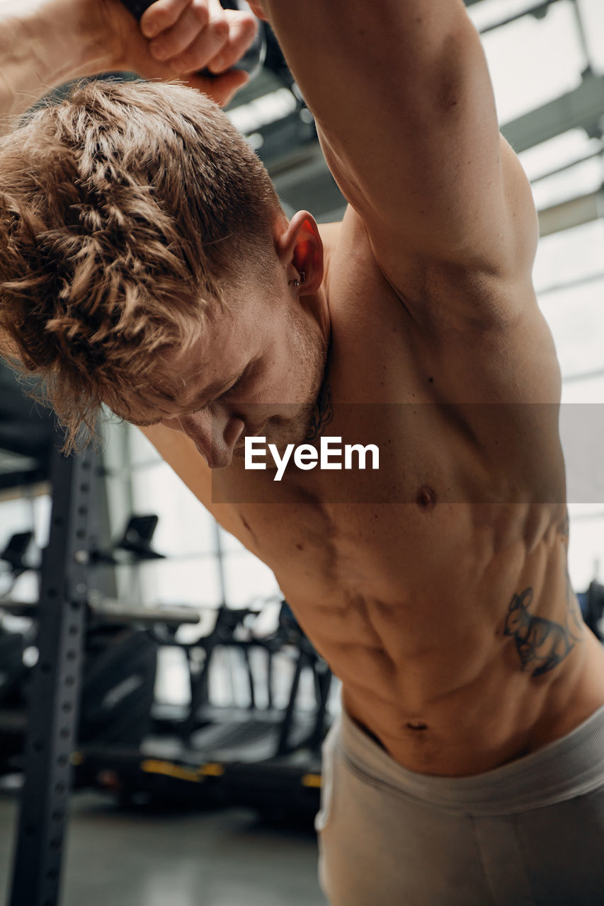 rear view of shirtless man exercising at gym