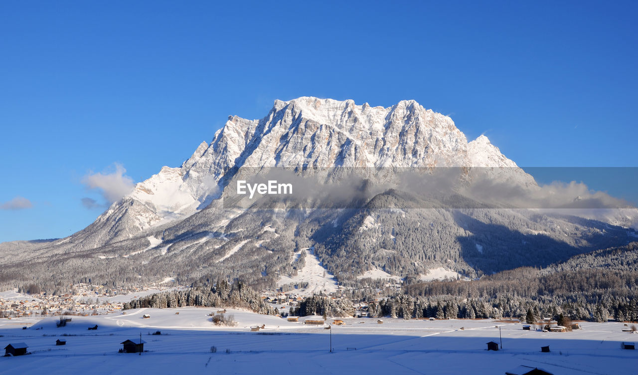 Scenic view of snowcapped mountains against blue sky