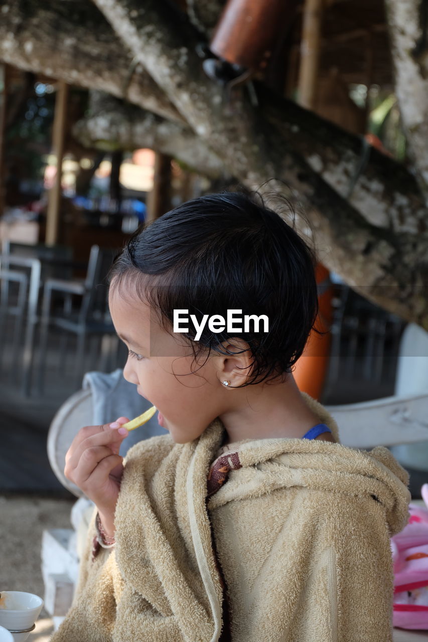 Girl eating food while sitting outdoors