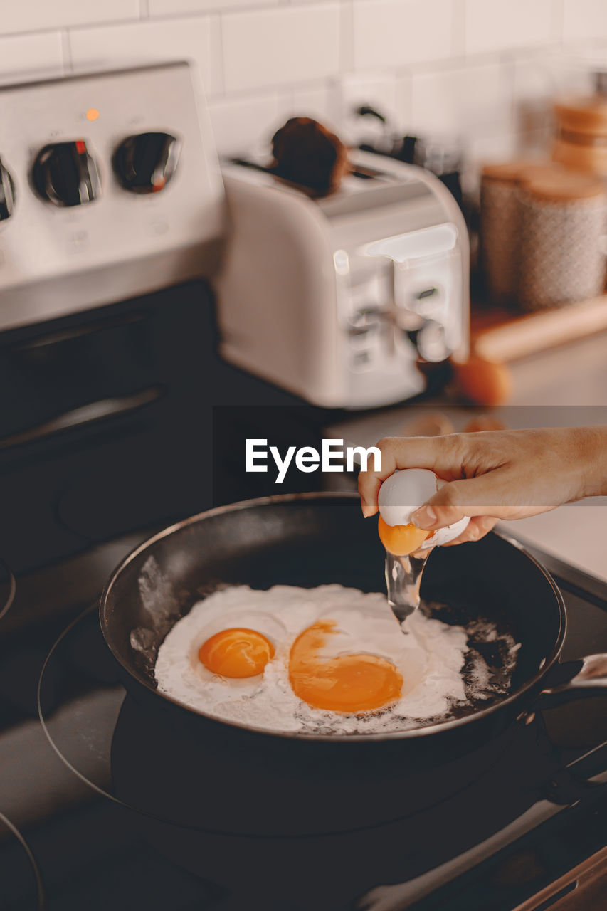 MIDSECTION OF PERSON HAVING BREAKFAST IN KITCHEN