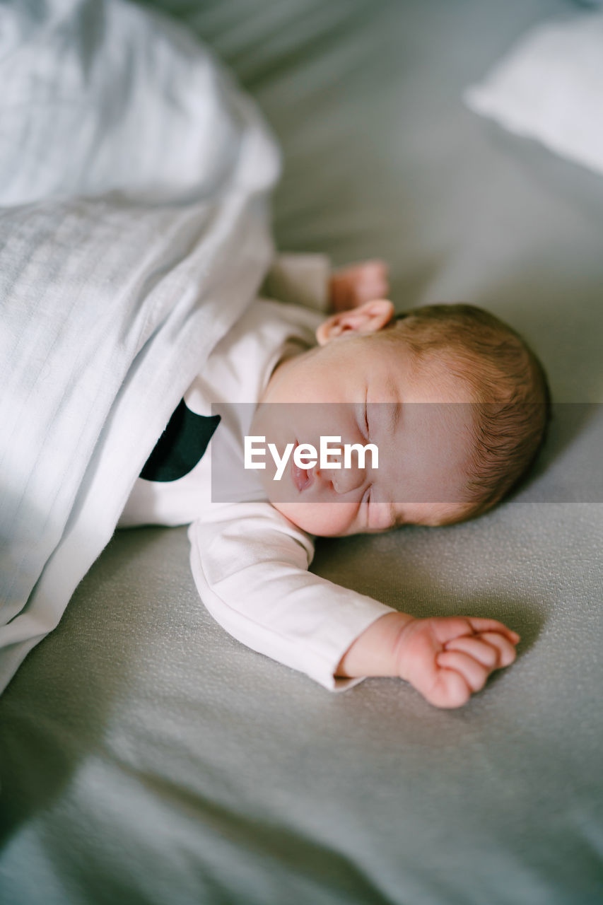 HIGH ANGLE VIEW OF BABY GIRL SLEEPING ON BED