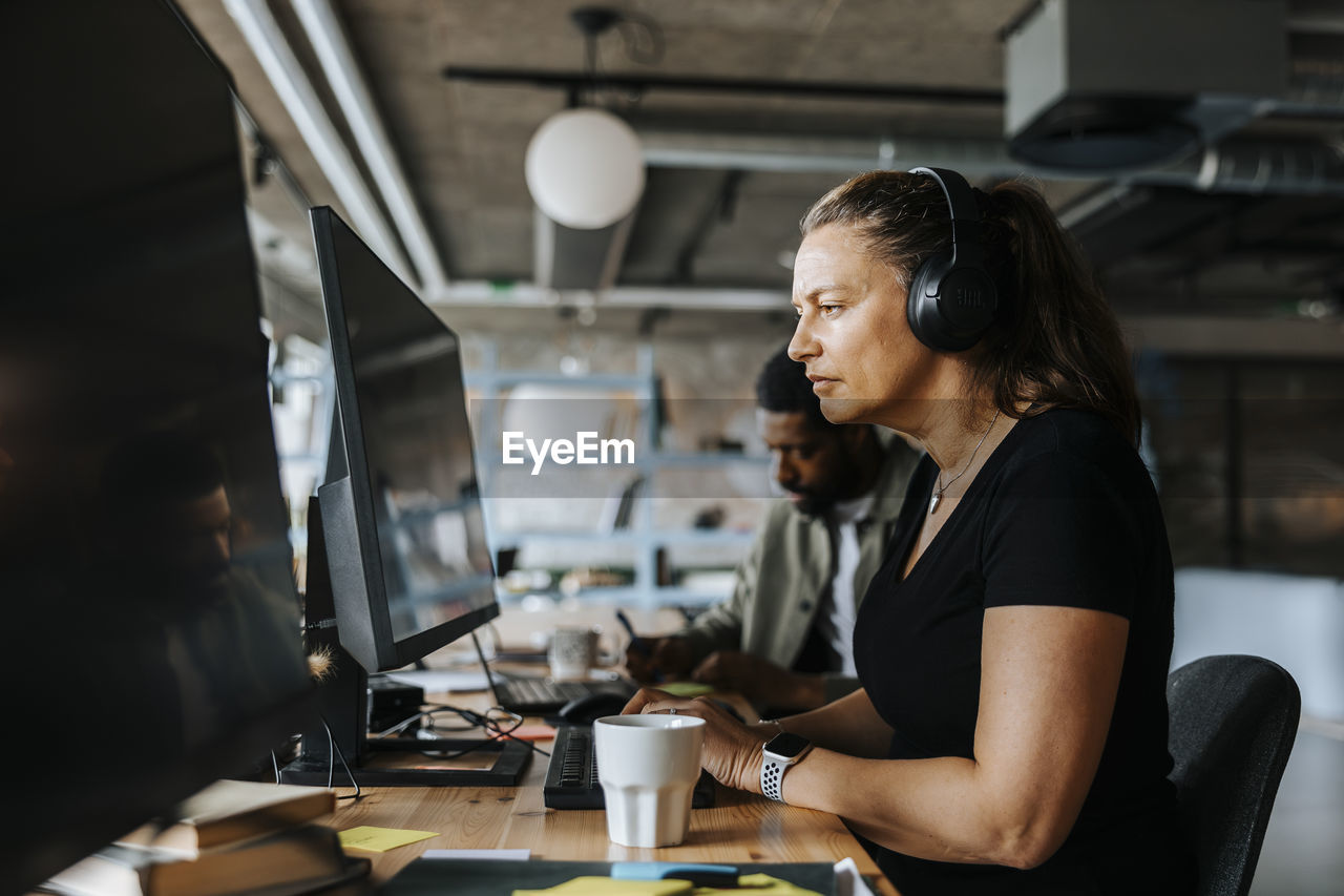 Focused female programmer coding while sitting at desk in tech start up office
