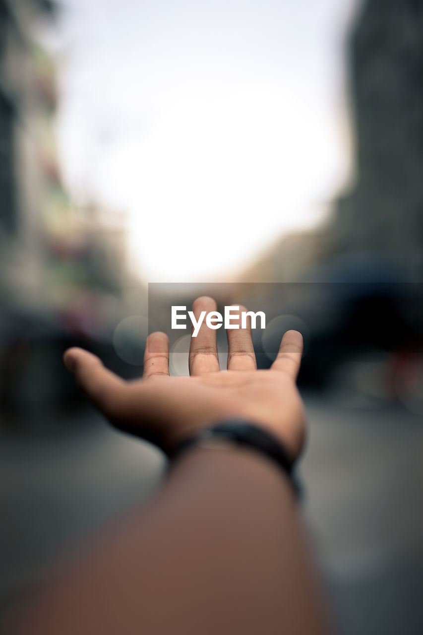 Close-up of human hand against sky