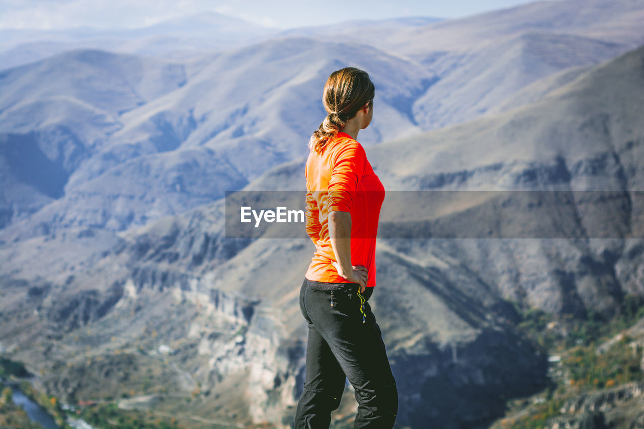 Side view of woman standing against mountains